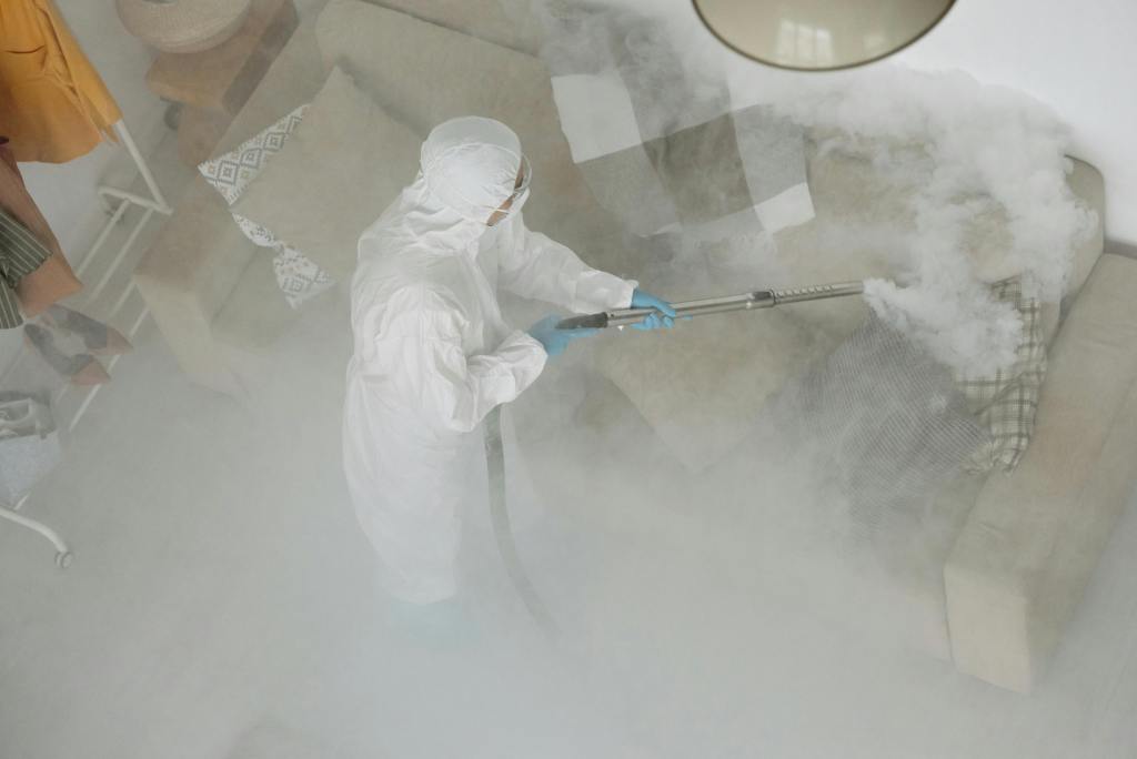 Technician in protective gear sanitizing a living room with smoke fumigation.